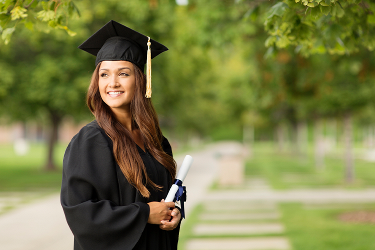 a female university graduate posing for a photograph at her graduation ceremony