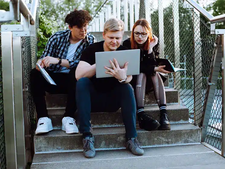 College students huddled in a group looking at a laptop