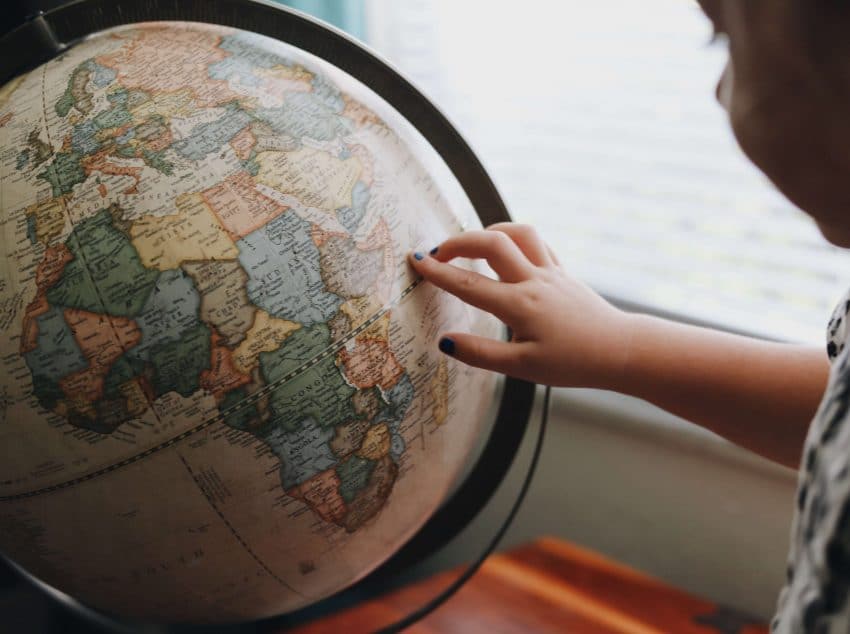 Child pointing finger on a globe