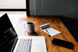 Writer’s desk with laptop, coffee, iphone and notebook with pen