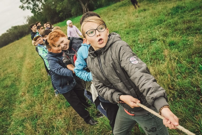 Students playing tug-o-war together in grassy field