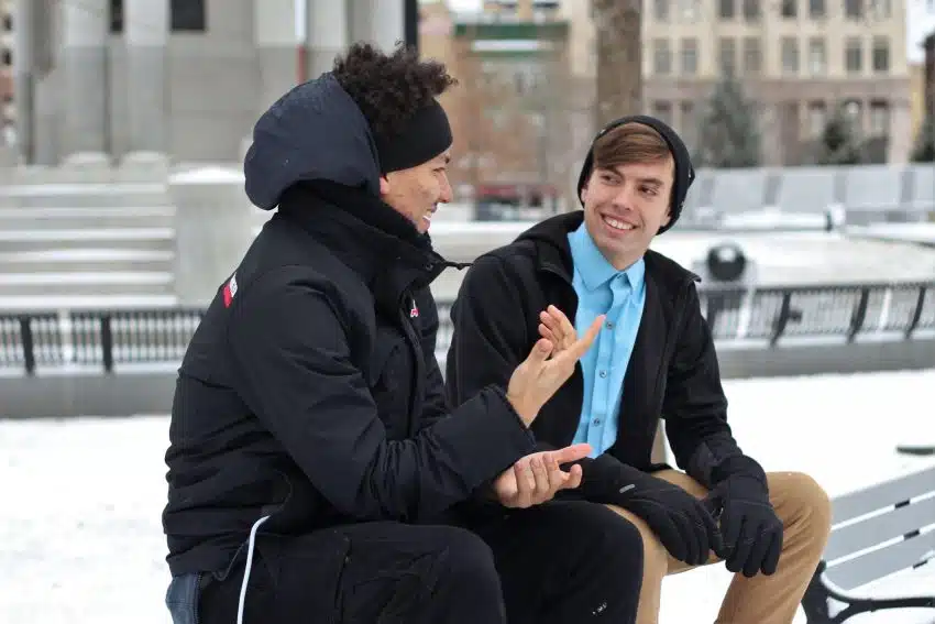 Two students sitting on bench talking in winter
