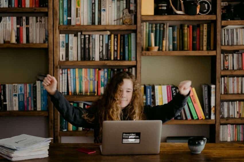 Young girl with fists up behind a laptop screen