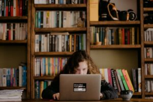 student in library studying liberal arts on laptop
