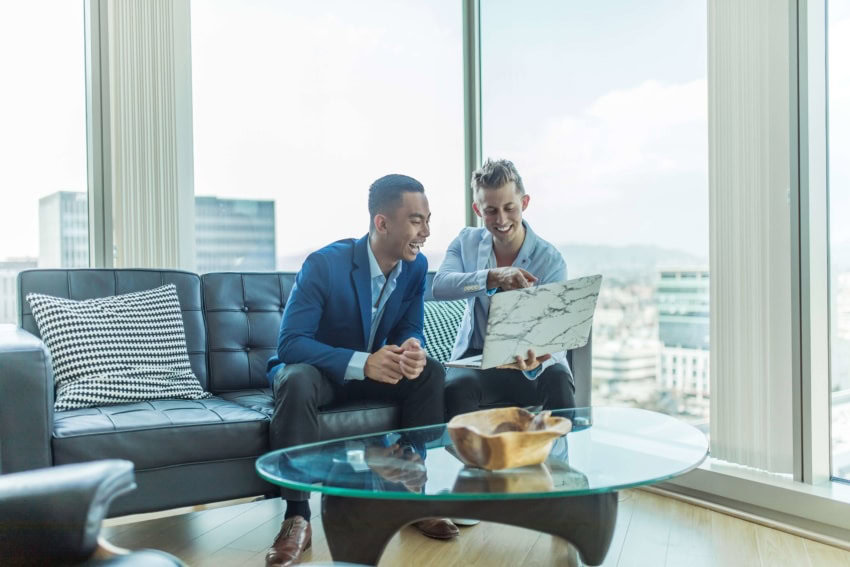 A business coach and client sit together with a laptop