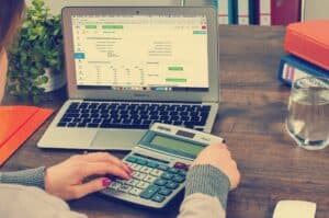 Person with financial education sitting at desk with calculator and laptop.