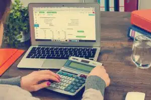 Person with financial education sitting at desk with calculator and laptop.