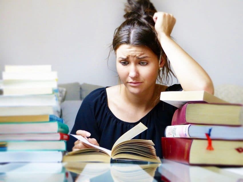 Woman with stressed expression sitting at table with books