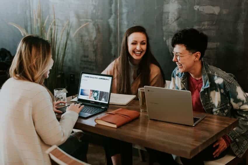 Group of women at table with computers and notebook