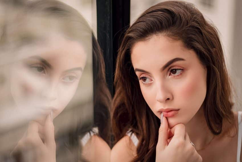 how critical thinking can be applied in school and life in general Woman deep into thought as she looks out the window, using her critical thinking skills to do some self-reflection.