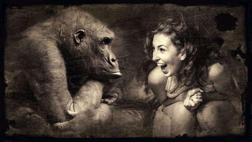 A laughing woman sitting across from an ape