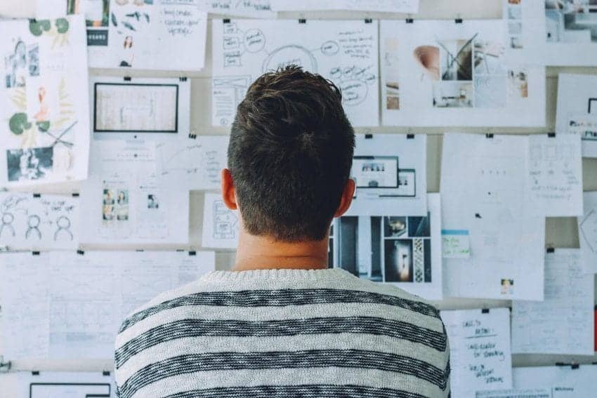 Man thinking critically in front of bulletin board