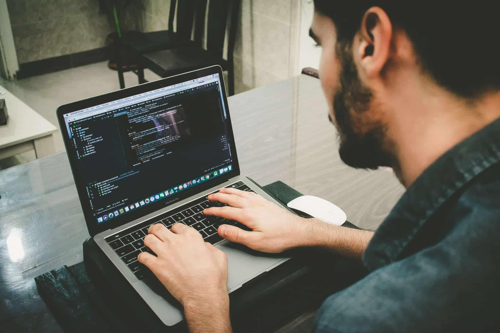 Man coding on open laptop computer