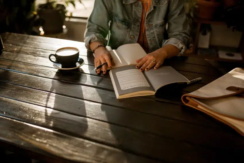 “University of the People student taking notes and reading at cafe”