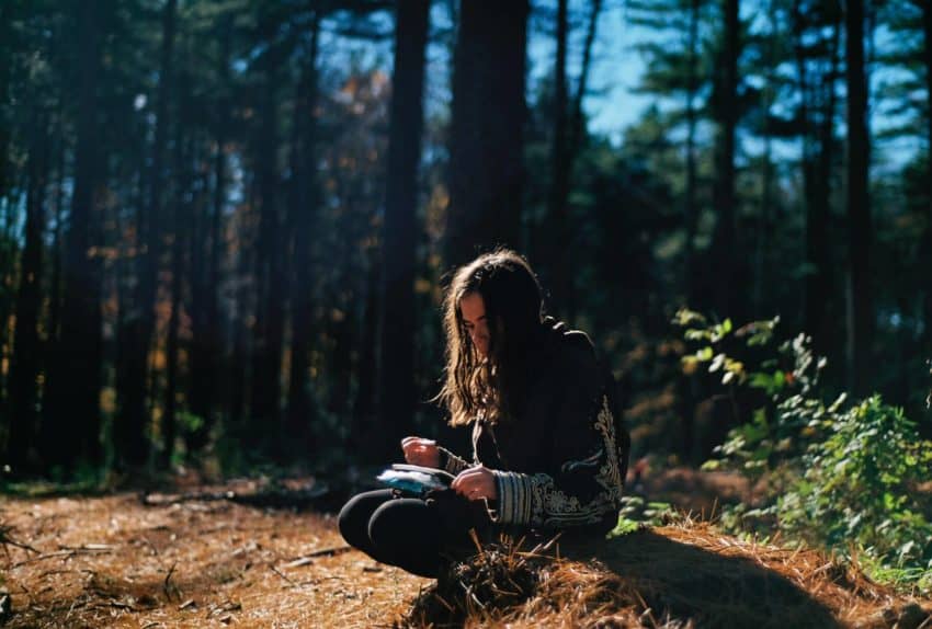 “Female with high intrapersonal intelligence journaling on a tree stump”