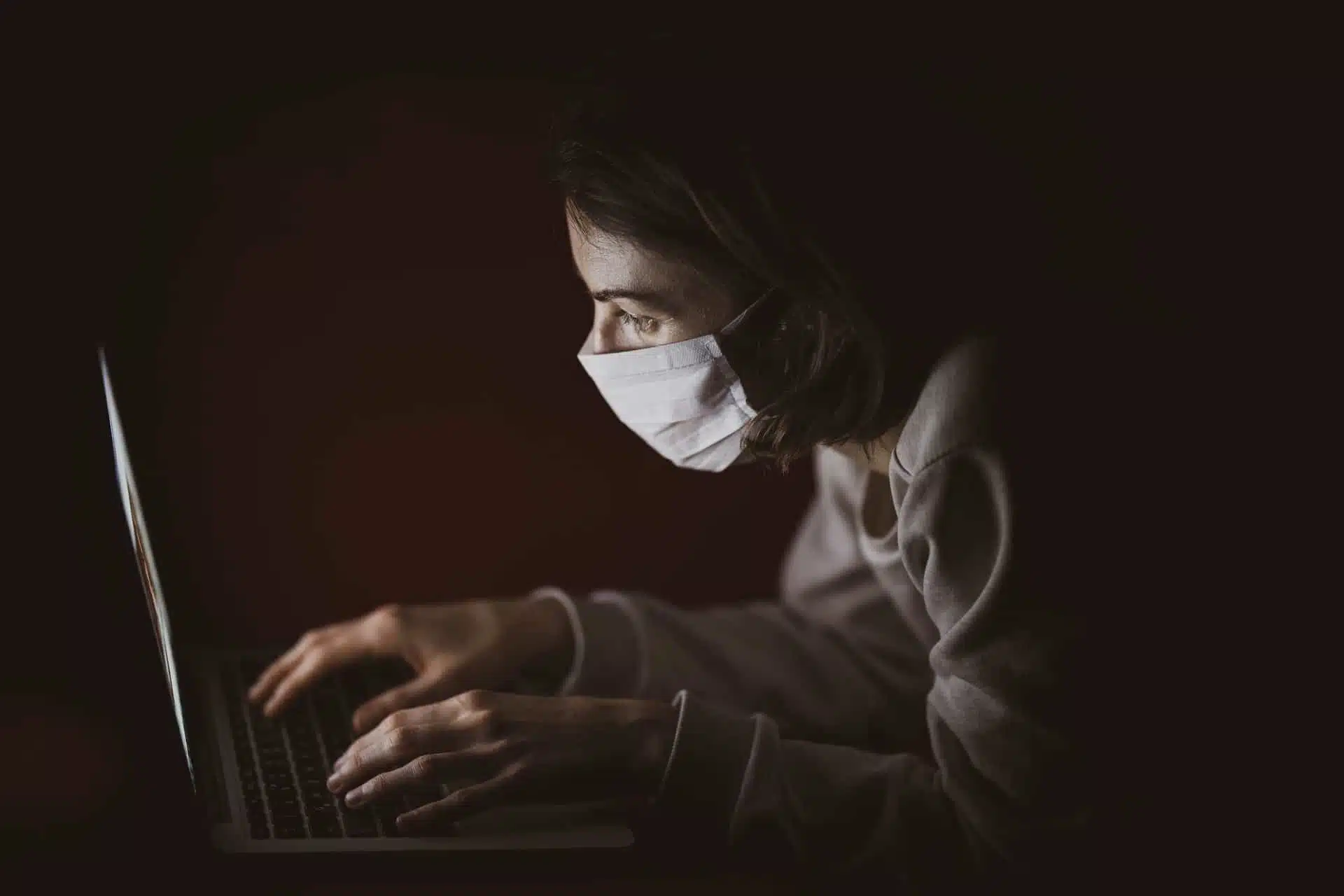 Student working on a laptop while wearing a face mask during COVID-19 pandemic