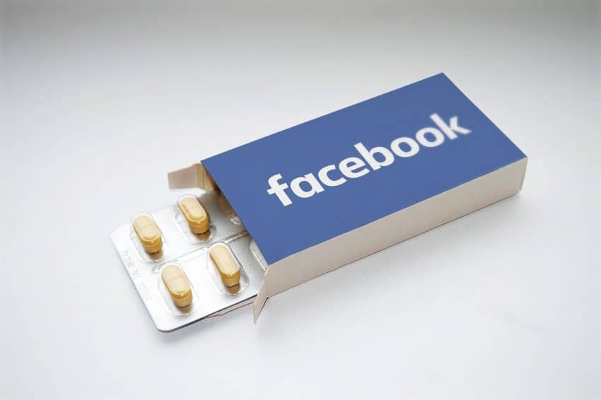 A pill box that says “Facebook” with yellow pills sticking out.