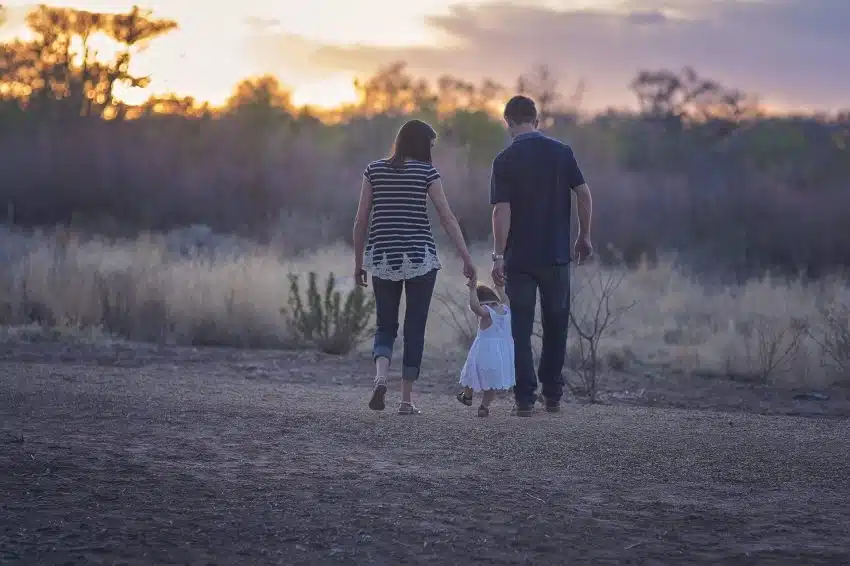 Mother and father walking with child through a field