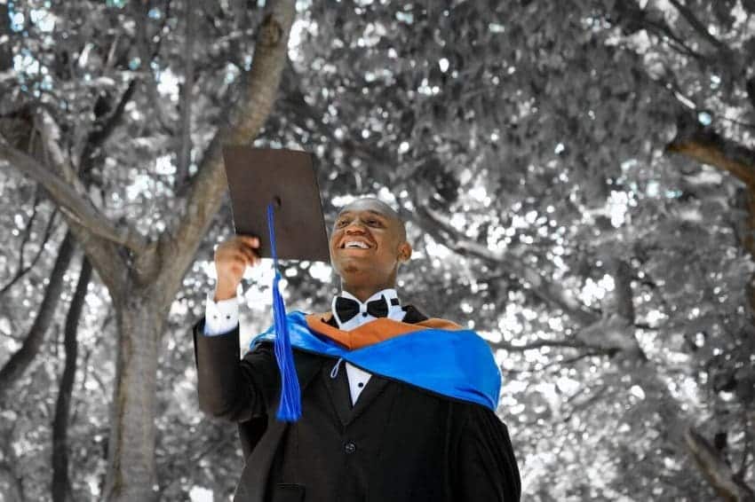 Smiling man in graduation gown holding a cap