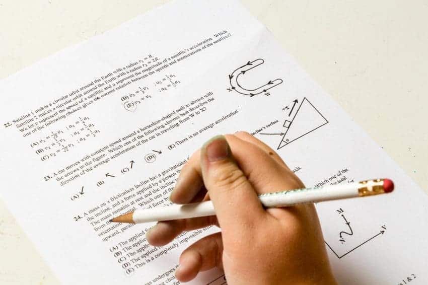 Student’s hand holding pencil above a math test