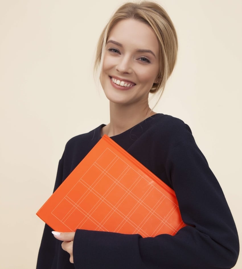 Smiling woman holding orange notebook