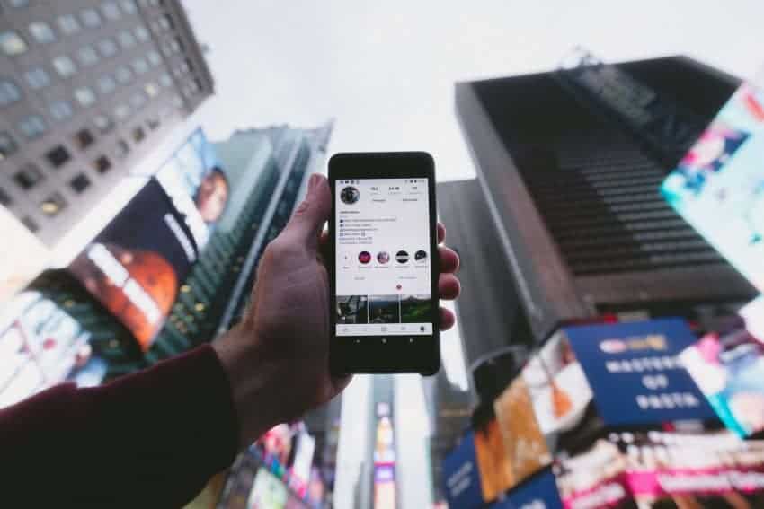 Man holding cell phone with instagram screen in front of buildings