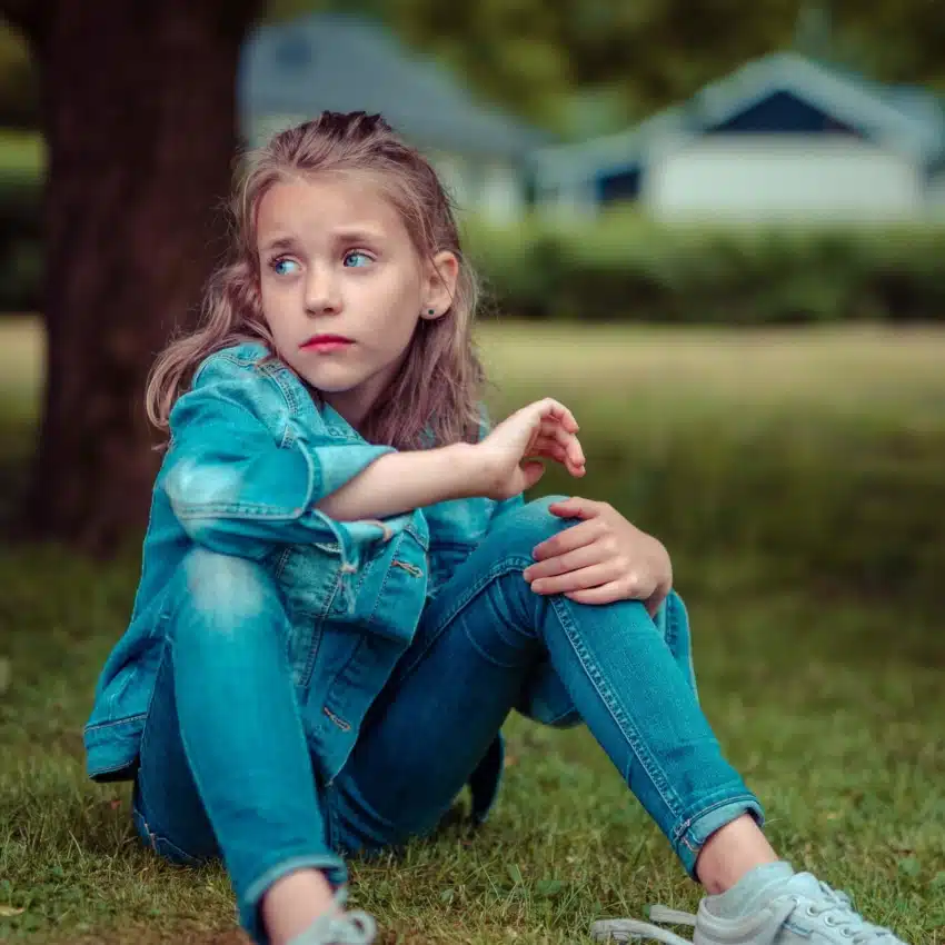 Child sitting on grass looking sad