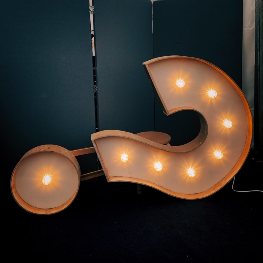 Light up question mark on its side against dark background