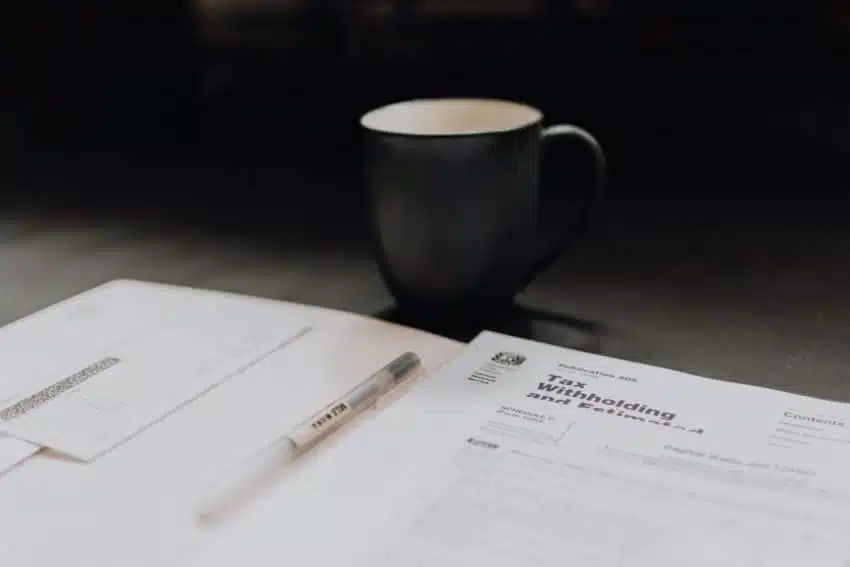 Tax forms in a folder and a cup of coffee