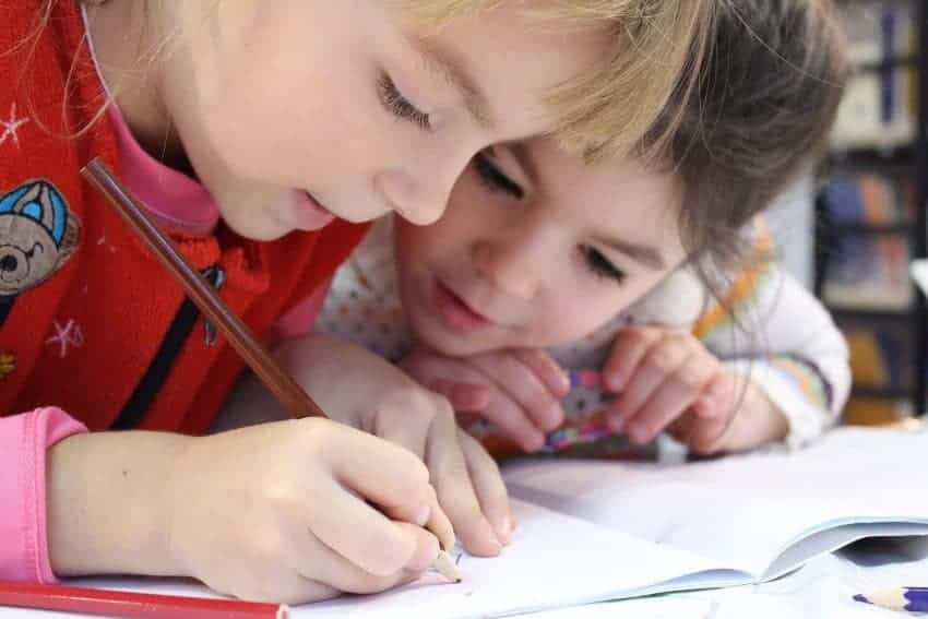 Two young girls studying and writing together