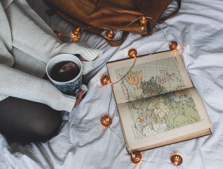 Girl on bed studying old maps