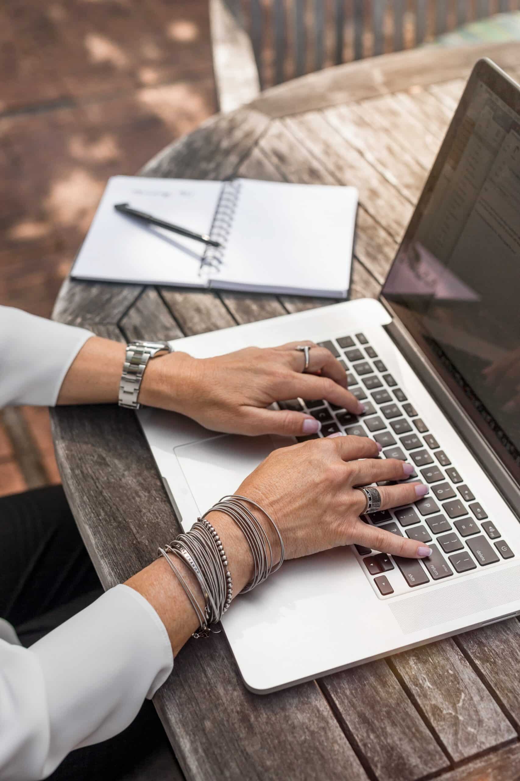 person typing on keyboard with notepad on table