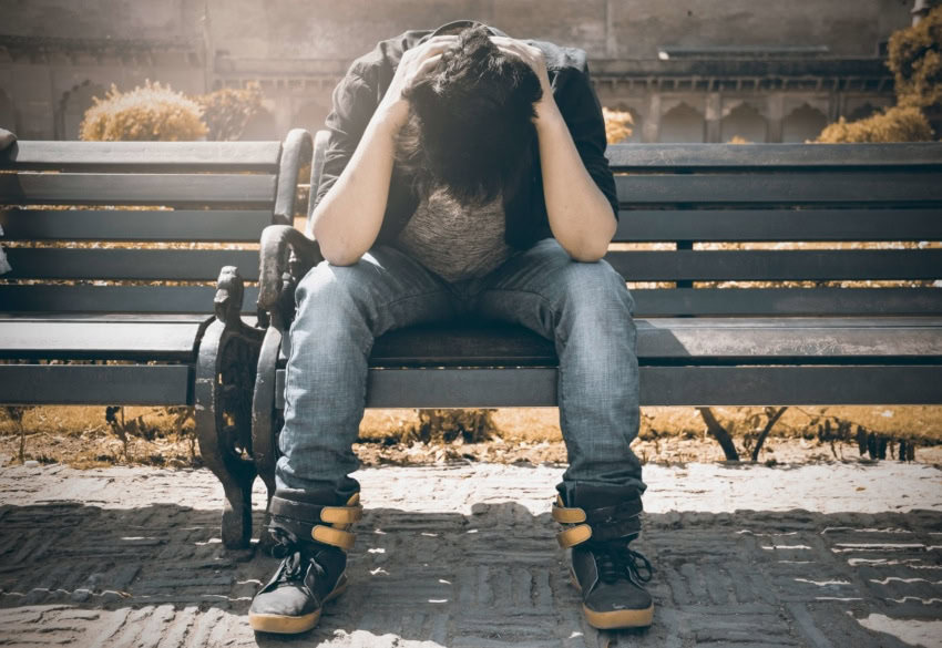 Student sitting on bench, visibly upset from being bullied in school