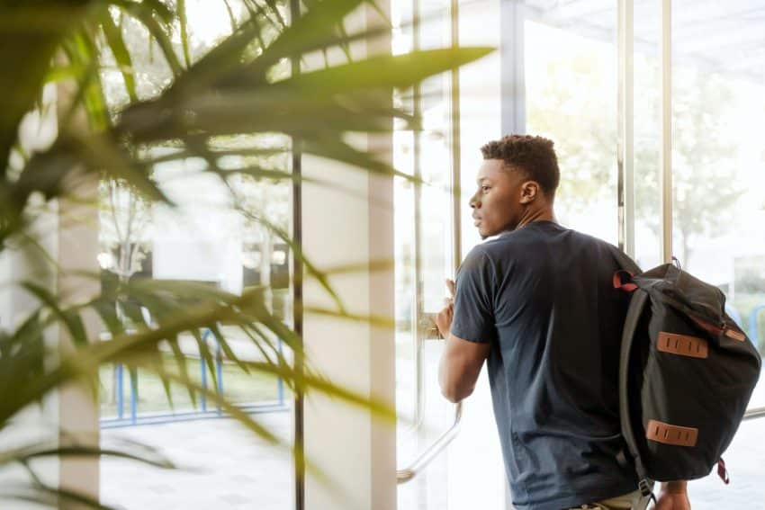 Man with backpack walking through college door