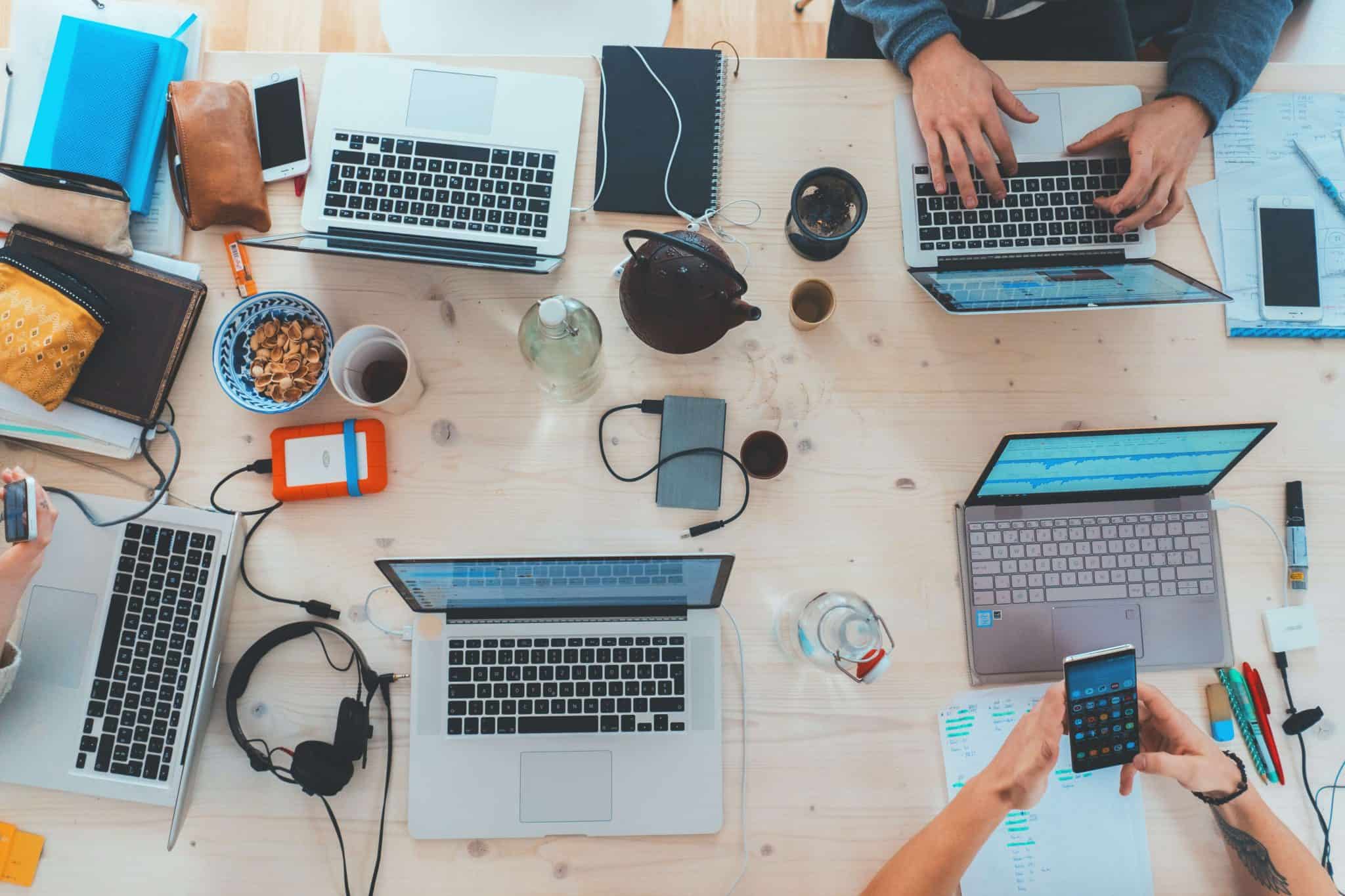 Multiple people working together at a table with laptops