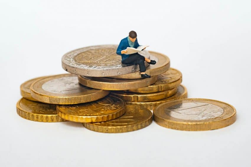 Man sitting on pile of coins reading a book