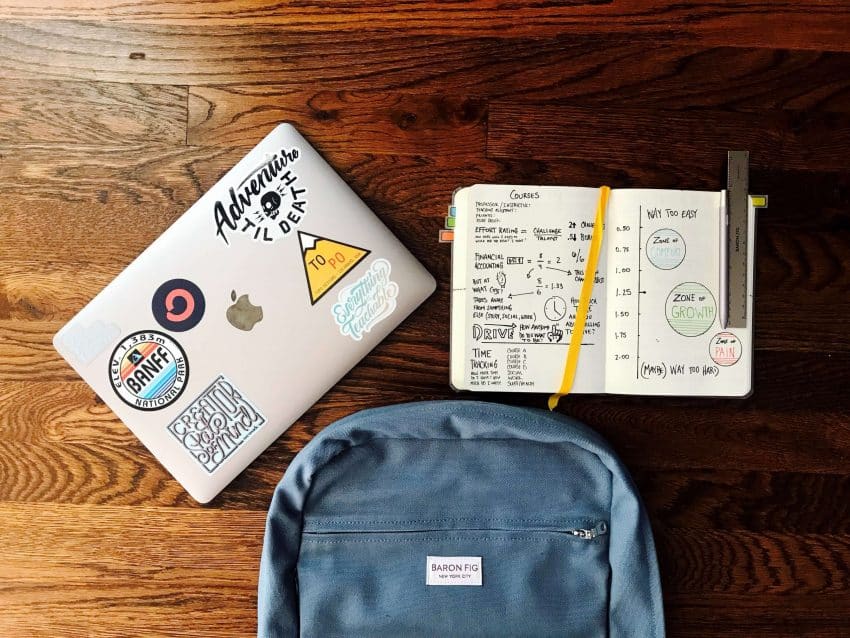 School desk with laptop, notebook and backpack