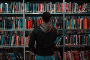 Man in black jacket standing in front of library bookshelves