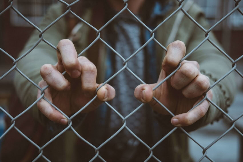 Student with both hands on chain link fence