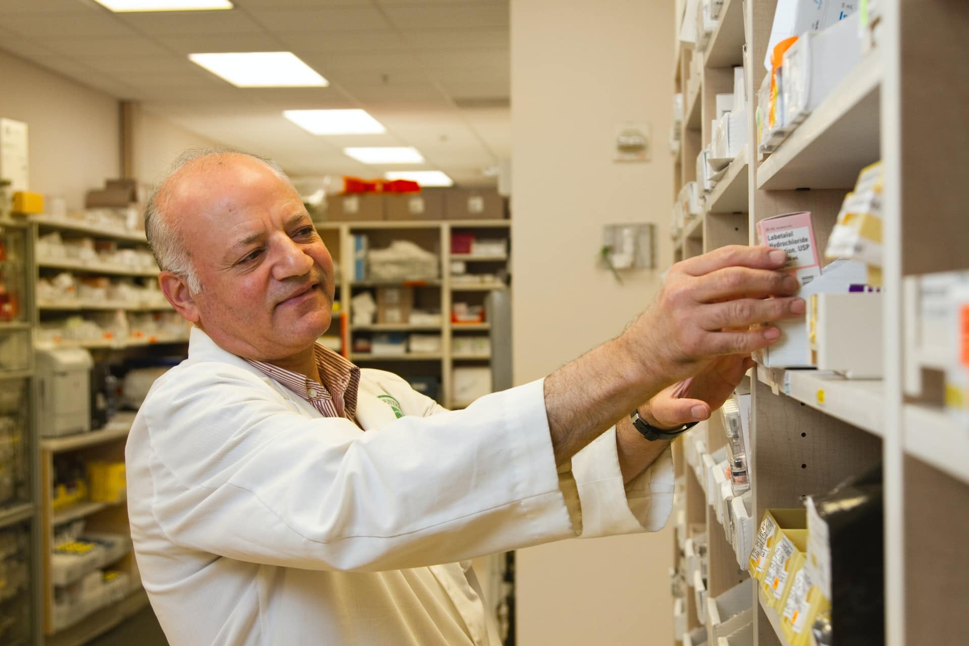 Pharmacist removing a medication from a pharmacy shelf /