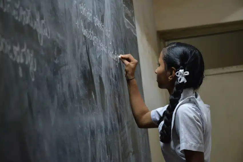 Young girl writing on a chalkboard in school