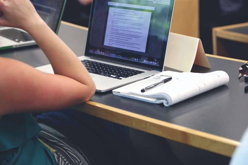 Student learning a US History AP Class and taking notes both on her computer and with pen and paper