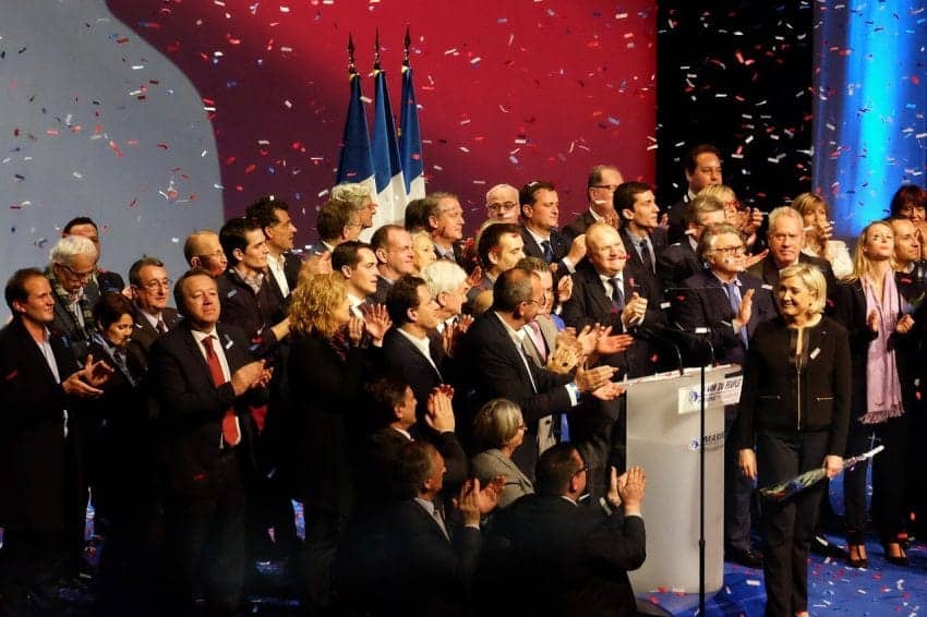 Crowd celebrating around podium with confetti falling