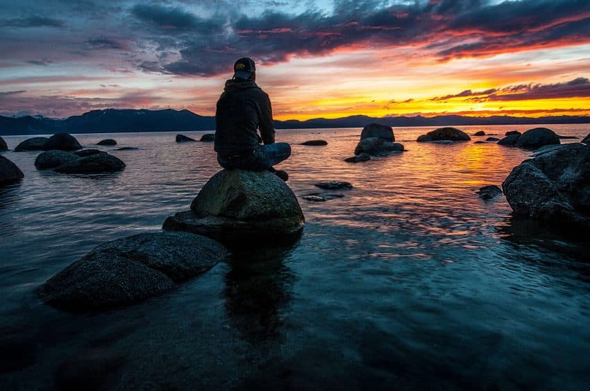 Watching the beautiful sunset while sitting on a rock and engaging in reflective thinking.