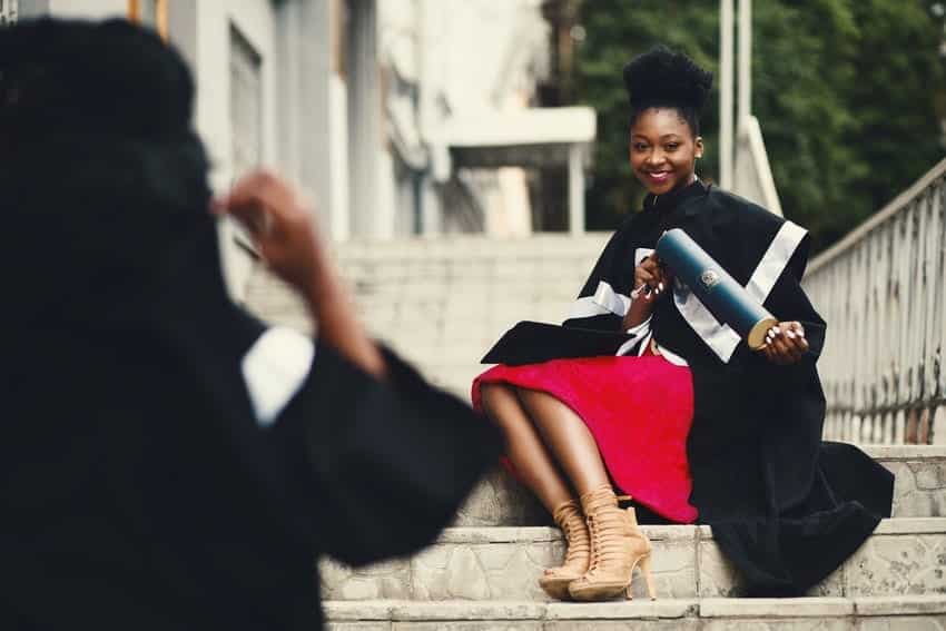 University graduate of BA or BS degree sitting with diploma