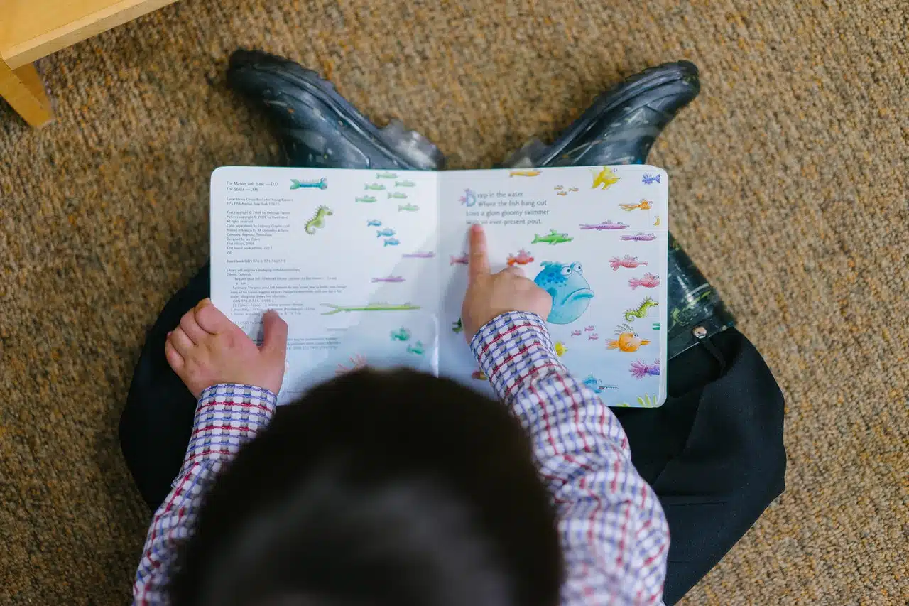 A young boy practicing his reading skills with the help of images to make sense of the text. 