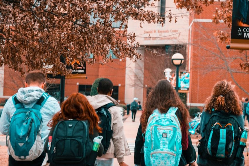 Students walking on college campus with backpacks