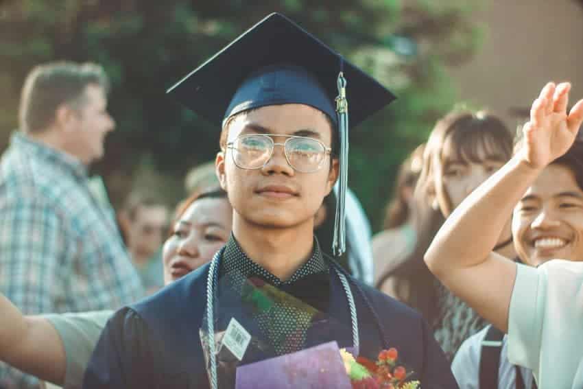 University of the People graduate in cap and gown outdoors with family