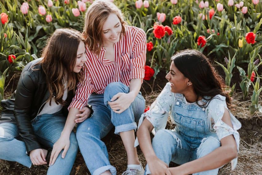 Three female University of the People students talking in tulip field