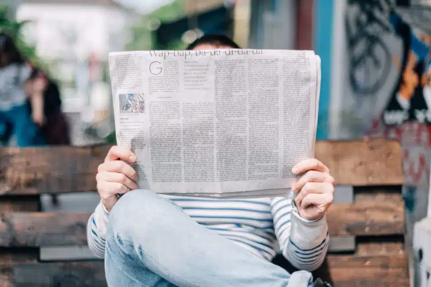“University of the People student reading newspaper on bench”
